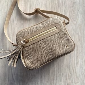 Bolso taupe manos libres con pompón en cuero